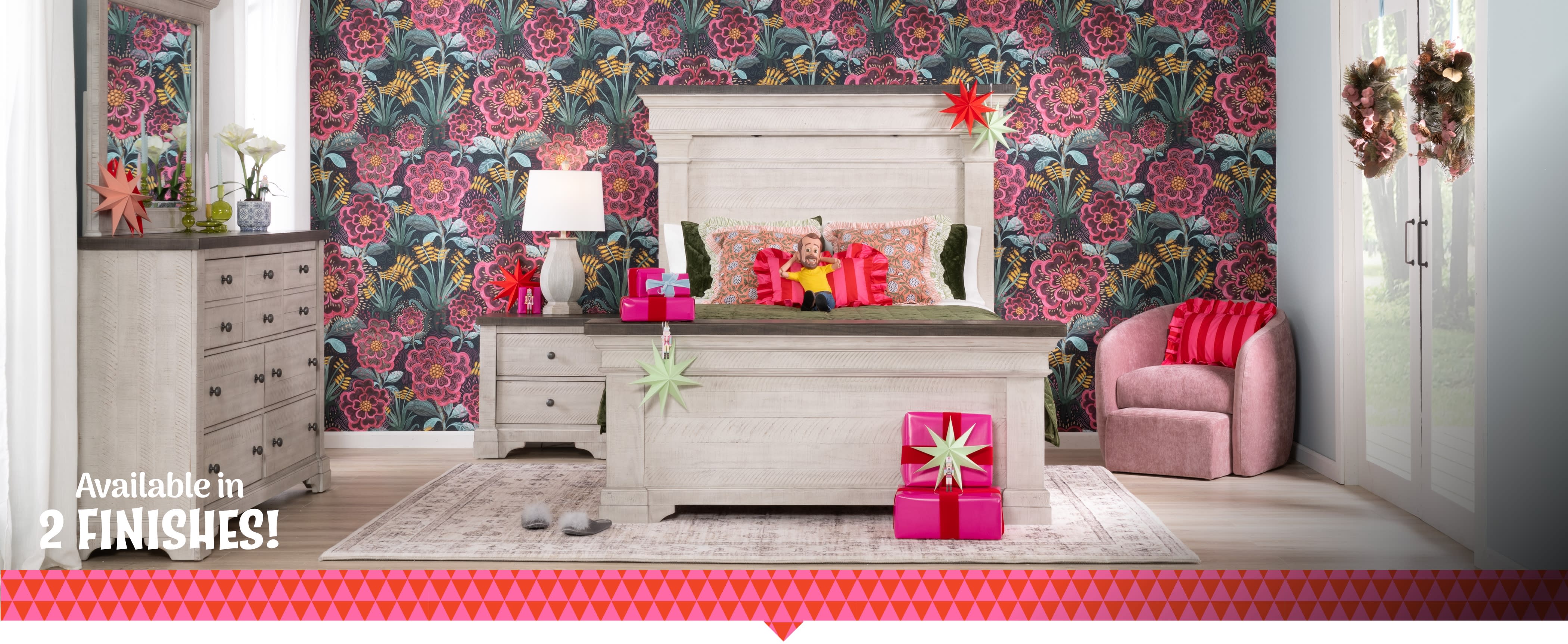 A stylish bedroom featuring a large white bed, colorful floral wallpaper, and wrapped gifts.