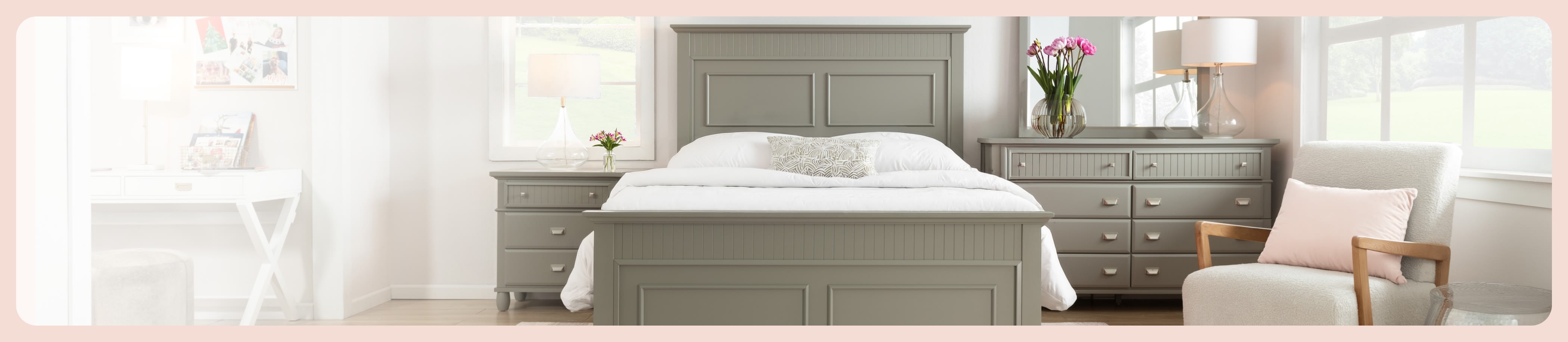 Modern bedroom with gray wooden bed frame, matching nightstands and dresser, white bedding, and a cozy armchair with a pink pillow.