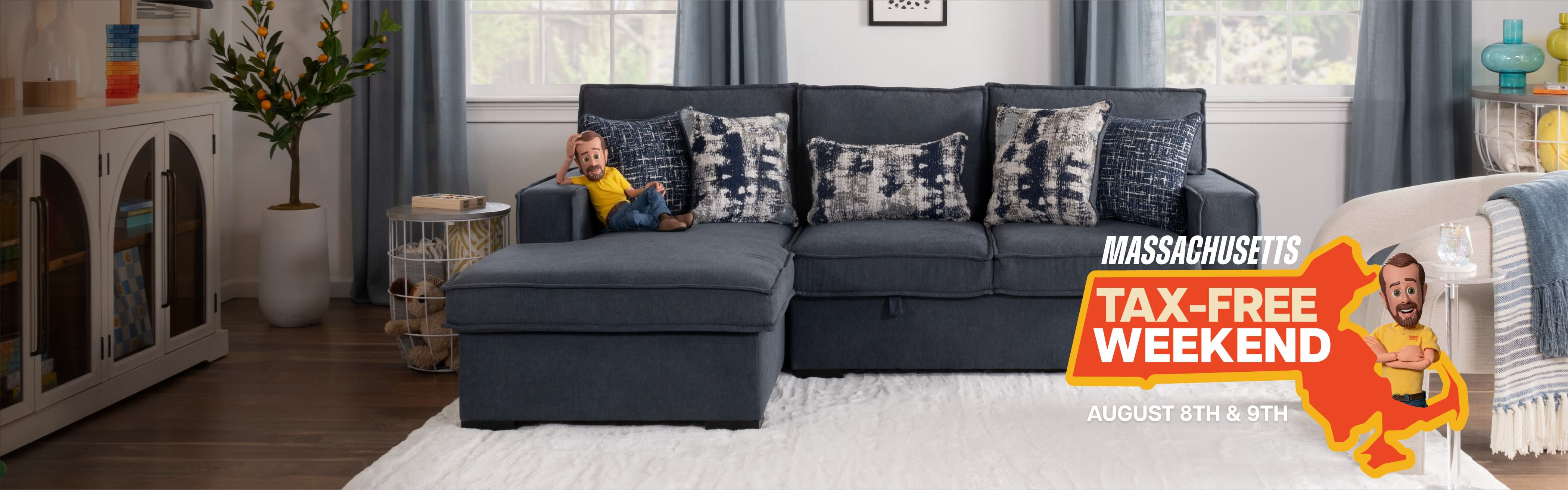 A blue sectional sofa with patterned pillows in a living room, with a graphic in the foreground that states “Massachusetts Tax-Free Weekend"