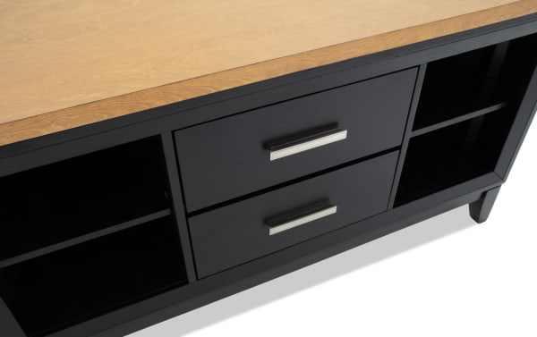 Black wooden TV stand with light wood top, featuring two central drawers with silver handles and open shelving on both sides.