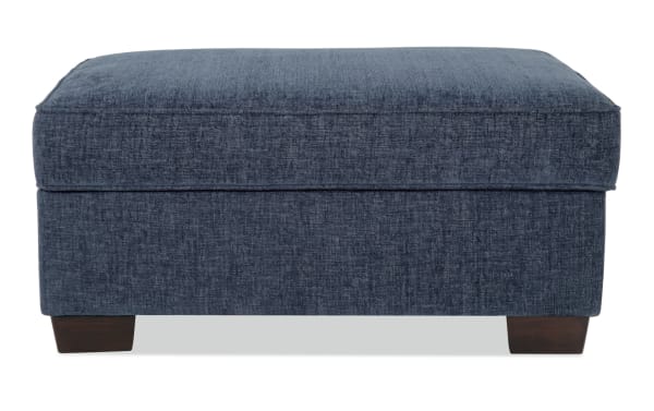 Brynn Navy Storage Ottoman in transitional style with soft navy polyester fabric upholstery, cushioned top, and hidden storage space.