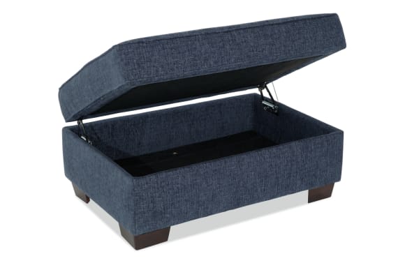 Brynn Navy Storage Ottoman in transitional style with navy polyester fabric upholstery, cushioned top, and spacious hidden storage compartment.