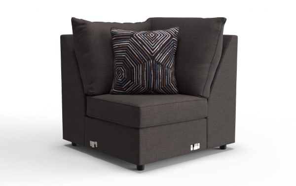 Dark gray fabric corner chair with plush cushions and a decorative geometric patterned throw pillow, featuring metal latch details on the base.