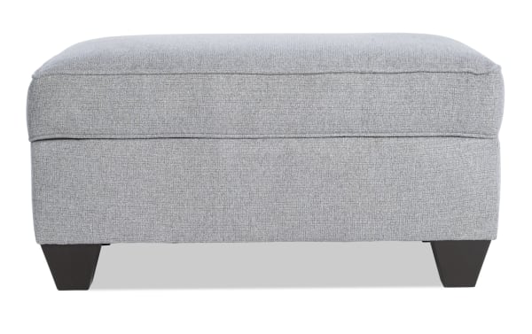 Gray Kylie Gray Storage Ottoman with soft polyester fabric upholstery, transitional style, cushioned top, tapered dark wooden legs, and hidden storage compartment.