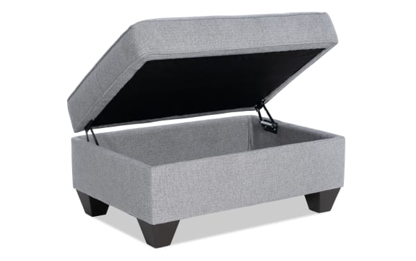Kylie Gray Storage Ottoman in transitional style with gray polyester fabric upholstery, cushioned top, no-sag spring seating, and hidden storage compartment.