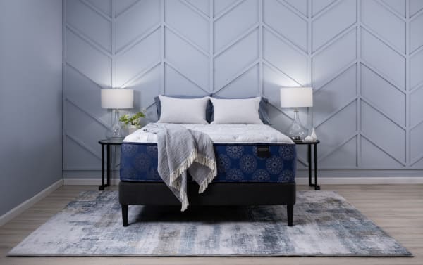Indulgence 15'' Queen Ultra Plush Mattress in blue floral pattern with gel-infused foam, memory foam, and coil system on black bed frame, styled with gray throw and pillows.