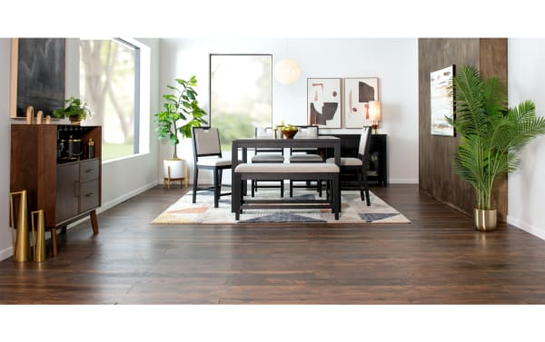 Brookline Black Square Dining Table in transitional style with solid acacia wood, rubberwood solids, oak veneers, paired with cushioned chairs and bench on a patterned rug in a modern dining room.