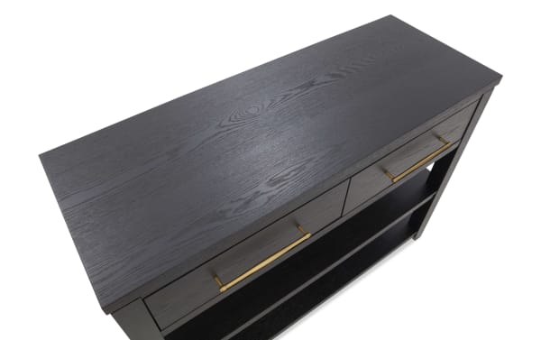 Dark wood console table with two drawers featuring long brass handles and an open lower shelf, showcasing a modern, sleek design.