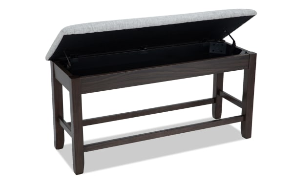 Homeworks Dark Brown & Gray Upholstered Counter Height Storage Dining Bench with soft gray polyester seat, dark wood frame, and lift-top storage compartment.