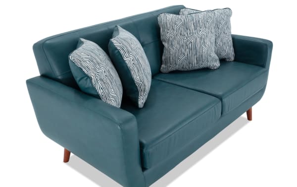 Bettie Teal Faux Leather 65'' Loveseat in mid-century modern style with teal faux leather upholstery, four patterned fabric accent pillows, track arms, and wooden legs.