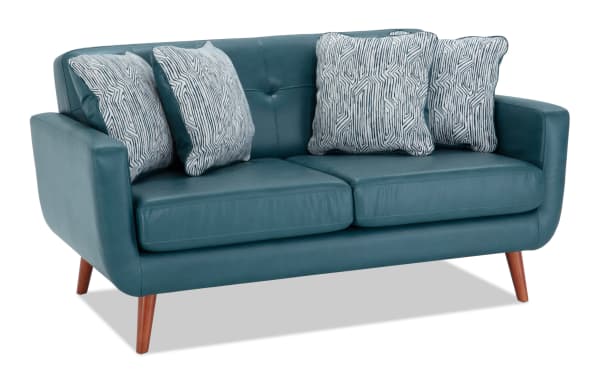 Bettie Teal Faux Leather 65" Loveseat in mid-century modern style with teal faux leather, four patterned polyester pillows, tufted back, and wooden legs.