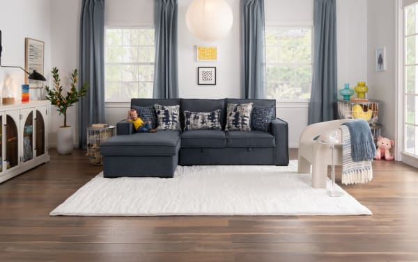 Transitional Playmax Gray & Denim Accent Chair with polyester fabric upholstery, Bob-O-Pedic memory foam seating, and cozy throw blankets in a bright living room.