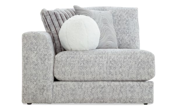 Modern gray fabric sectional sofa corner piece with thick cushions and three decorative pillows in white and textured gray tones, ideal for living room seating.