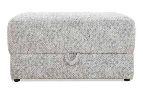Rectangular storage ottoman upholstered in soft, textured gray fabric with a subtle speckled pattern, featuring a pull tab for easy lid opening.