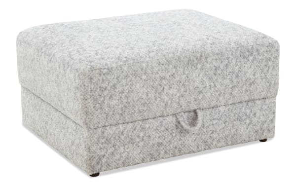 Gray fabric upholstered rectangular ottoman with storage, featuring a soft textured surface and a pull tab for easy access.