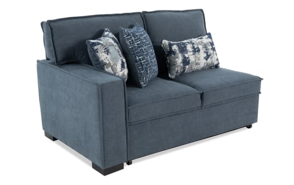 Blue fabric loveseat sofa with wide armrests, plush back cushions, and three decorative patterned throw pillows in blue and white tones.