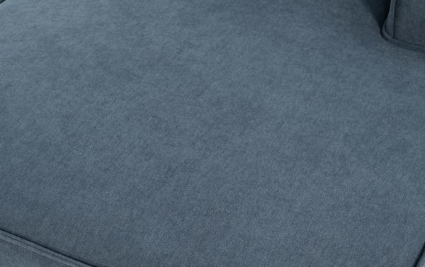 Close-up of a blue-gray fabric sofa cushion with a soft, textured upholstery and visible seam detailing.