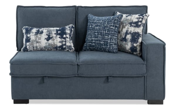 Blue fabric loveseat with two seat cushions, three decorative throw pillows in blue and white patterns, and a single armrest on the right side.