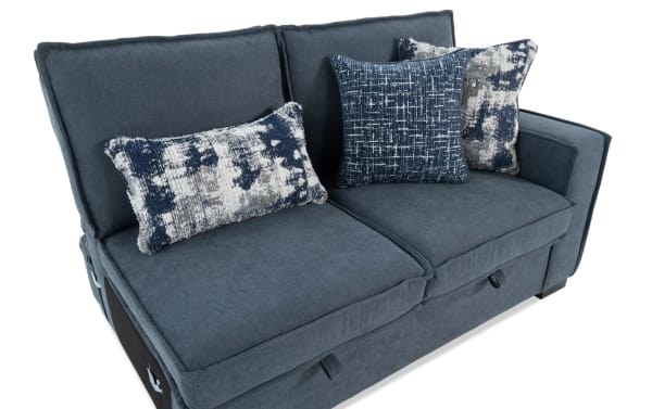 Blue fabric loveseat sofa with two seat cushions, three decorative blue and white patterned throw pillows, and a modern boxy arm design.