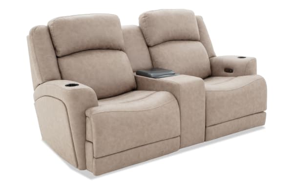 Beige leather dual reclining loveseat with cup holders and center console, featuring plush padded backrests and armrests for home theater seating.