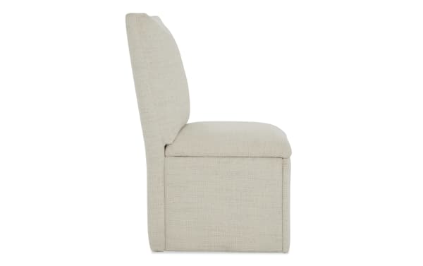 Upholstered beige fabric dining chair with cushioned seat and backrest, modern minimalist design, side view.