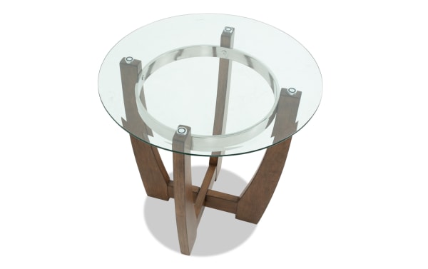 Round glass top side table with a clear tempered glass surface, supported by a dark wood base with four curved legs and metal accents.