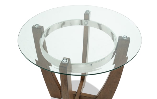 Round glass top table with a clear tempered glass surface, supported by four dark wood curved legs and a metal ring frame.