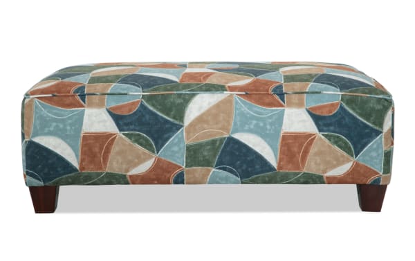 Brynn Green Ottoman from the Brynn collection, featuring a transitional style with green, blue, tan, and white geometric polyester fabric upholstery and cushioned foam for comfortable seating or footrest.