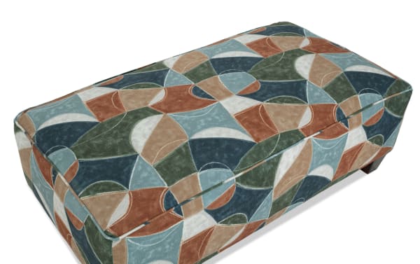 Brynn Green Ottoman from the Brynn collection features a transitional style with multicolor geometric fabric upholstery in green, blue, and rust tones. Made with soft polyester fabric and cushioned foam, this patterned ottoman offers cozy additional seating or a stylish footrest for living spaces.