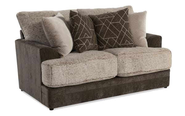 Two-seater loveseat sofa with plush beige sherpa cushions, dark brown microfiber base and armrests, featuring four decorative throw pillows with geometric and honeycomb patterns.