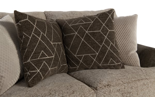 Beige textured fabric sofa with two dark brown geometric patterned throw pillows and two light beige velvet cushions, showcasing modern living room decor.