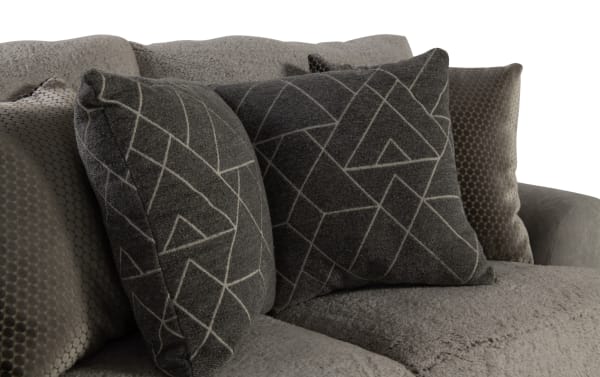 Gray textured fabric sofa with plush geometric-patterned and honeycomb velvet throw pillows, showcasing modern living room decor.