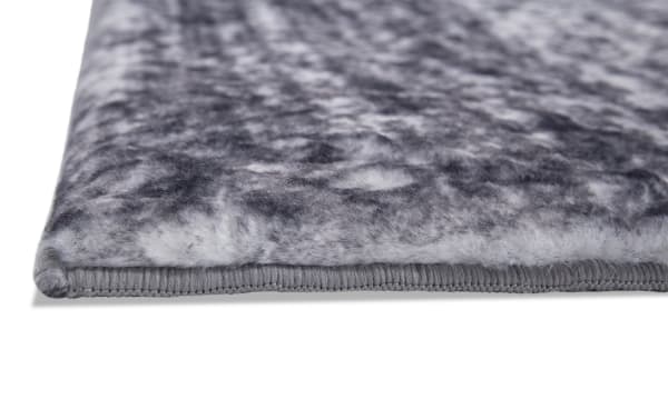 Close-up of Angora 5' x 7' Gray Abstract Rug edge, showing soft polyester fabric with gray transitional pattern and durable stitched border.