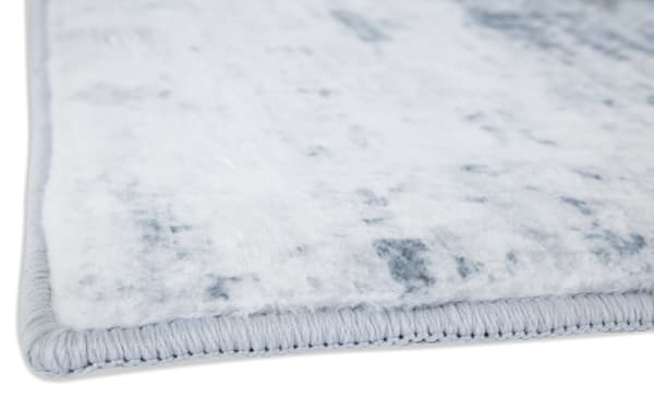 Close-up of the Angora 5' x 7' Teal Abstract Rug corner showing plush teal polyester fabric with dense 15mm memory foam and reinforced stitched edges for durability and comfort in transitional home decor.