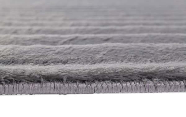 Close-up of the Sofia Channel 5' x 7' Charcoal Solid Rug edge, showing soft gray polyester fabric with plush Bob-O-Pedic Memory Foam cushioning and detailed stitching in a transitional style.