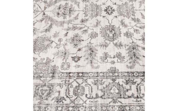 Vintage-style area rug with a faded gray floral and geometric pattern on a light beige background, featuring a distressed border design.