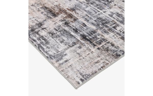 Abstract patterned area rug with a distressed design in shades of gray, beige, and brown, featuring a low pile and tightly bound edges.