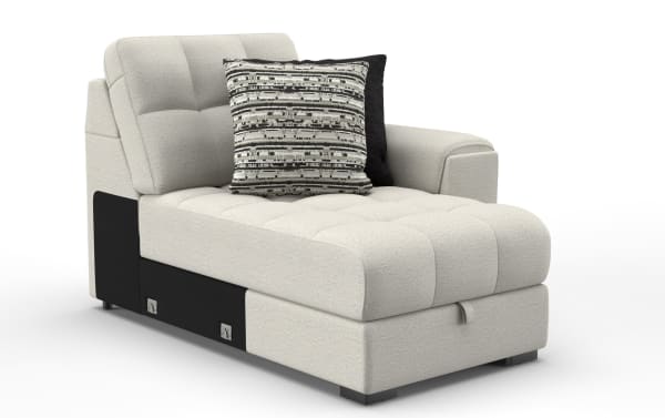 Modern beige fabric chaise lounge with tufted cushioning, black side panel, and two decorative pillows in neutral tones, ideal for living room seating.