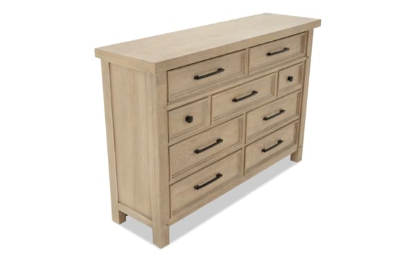 Light wood dresser with nine drawers featuring black metal handles and knobs, showcasing a rustic, farmhouse style storage solution.
