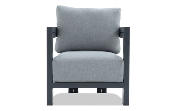 Modern outdoor armchair with dark gray metal frame and thick light gray fabric cushions, designed for patio or garden seating.