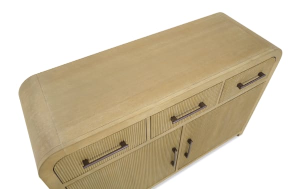 Light wood sideboard with rounded edges, ribbed drawer and door fronts, and dark metal handles, suitable for modern living spaces.