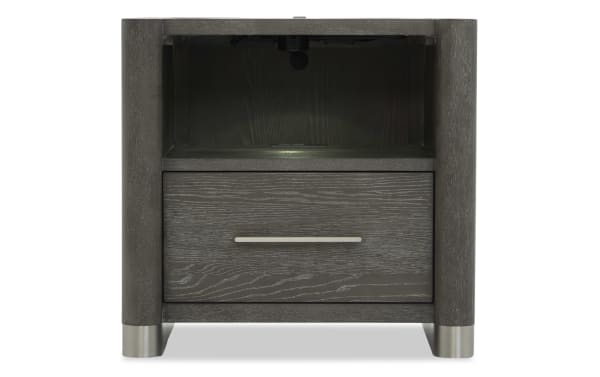 Dark gray wooden nightstand with rounded corners, a single drawer with a horizontal metal handle, open shelf above, and metal feet.