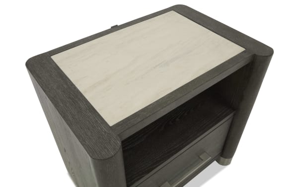 Modern dark wood nightstand with a light beige stone top, featuring an open shelf and a drawer with a metal handle, showcasing a sleek, contemporary design.