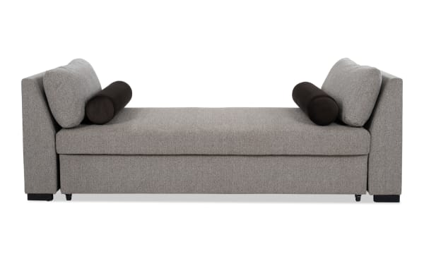 Transitional brown Daydreamer daybed with pop-up sleeper, upholstered in soft polyester fabric with memory foam cushioning and cylindrical bolster pillows.