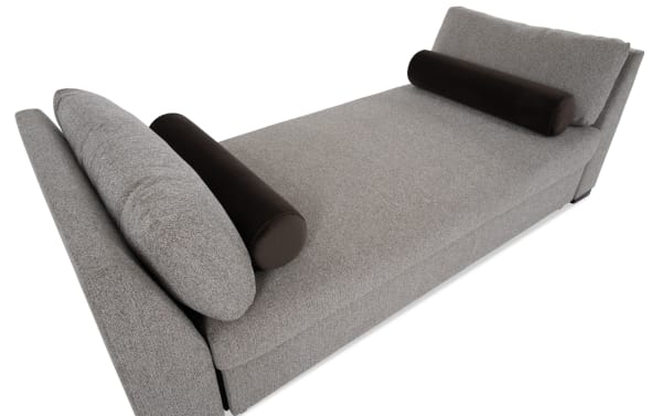 Transitional brown Daydreamer daybed with pop-up sleeper, upholstered in soft polyester fabric with memory foam cushioning and cylindrical bolster pillows.