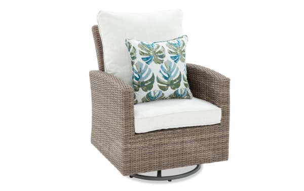 Outdoor swivel chair with taupe synthetic wicker frame, white cushioned seat and back, and decorative blue-green leaf patterned throw pillow.