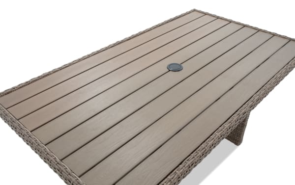 Rectangular outdoor dining table with light brown synthetic wicker frame and wood-look composite slatted tabletop featuring a central umbrella hole.