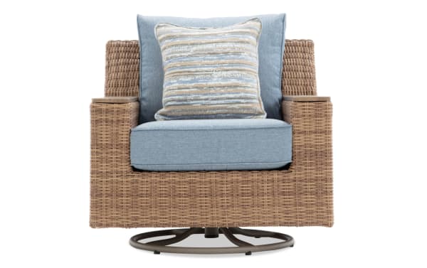 Wicker swivel armchair with light blue cushioned seat, backrest, and striped accent pillow, featuring a circular metal base.