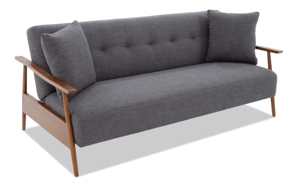 Bettie Ash Futon in gray polyester fabric with mid-century modern wood trim, tufted back, wooden arms, and two matching accent pillows.