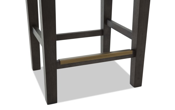 Dark brown wooden stool legs with a bronze metal footrest bar, part of the contemporary Encore Brown & Beige Backless Upholstered Counter Height Stool.